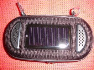 Case outside, showing the carabiners on top. The white dot on the left side of the solar panel is the blue 'charging' LED