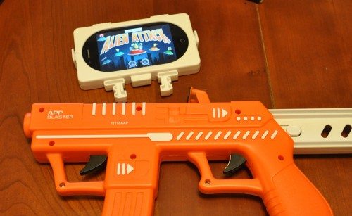 AppBlaster, showing the device holder with an iPhone 4s. This clips onto the barrel in the slot just forward of the rear trigger, so that the two tap pads can touch the screen. Note the locking sliders on the side to secure the device holder onto the controller.