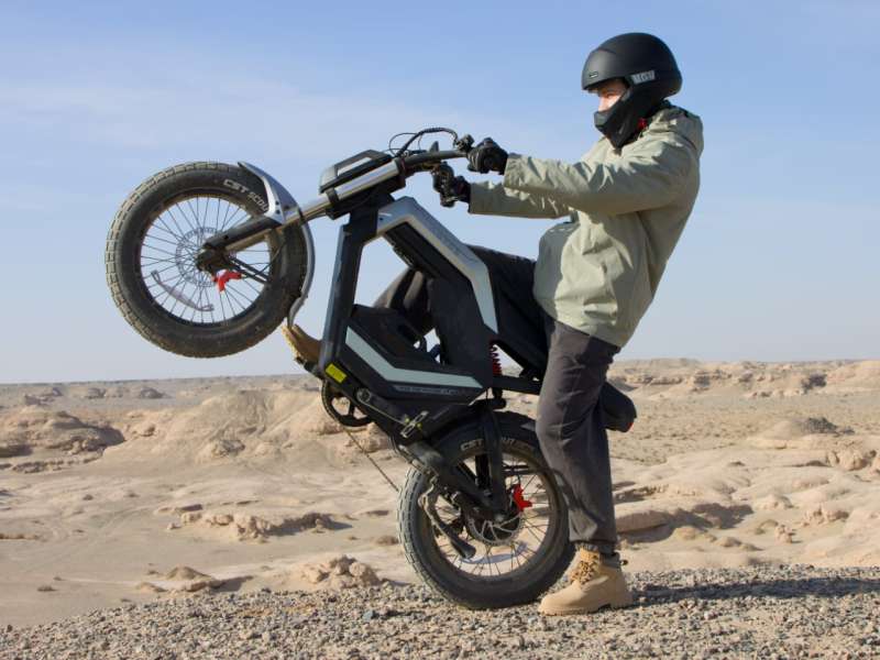 AOTOS Flux X26 electric motorcycle riding through city streets and desert terrain with 48V battery system, long range performance, and all weather IPX5 design