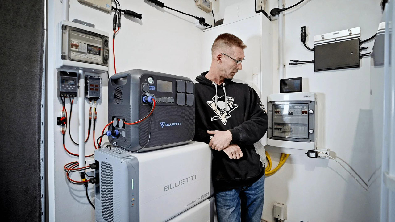 A sleek, white BLUETTI EnergyPro 13K whole home battery backup system installed against a modern garage wall next to a parked electric vehicle.