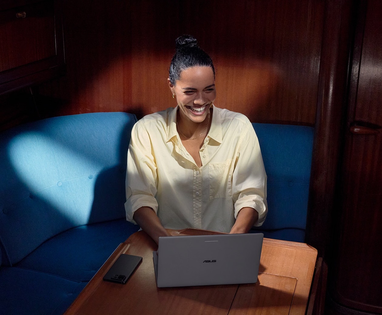 Woman using an ASUS Googlebook 14 at a table below deck