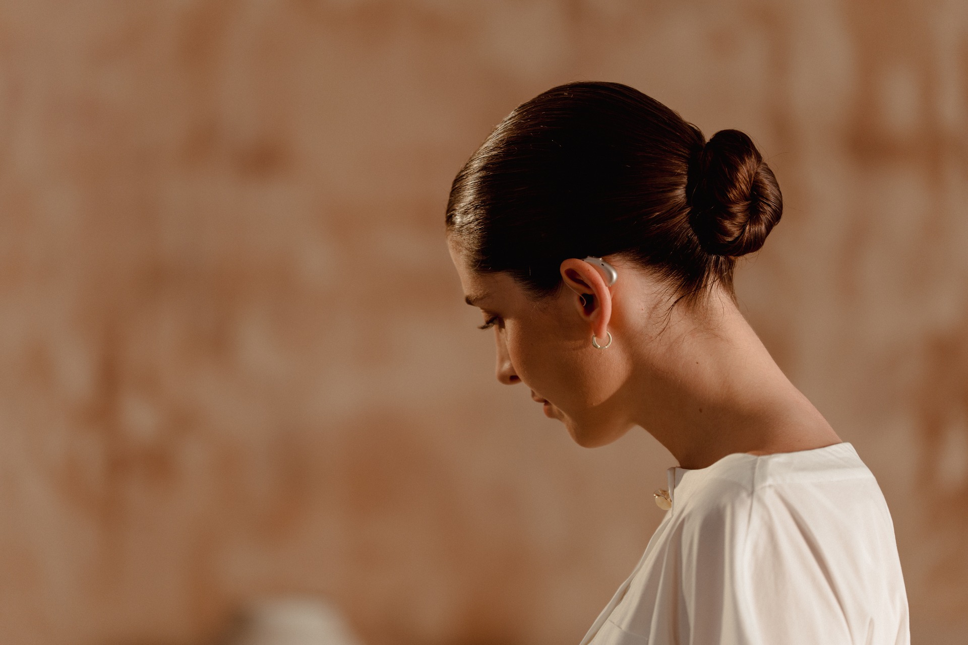 Side view of a woman wearing an ELEHEAR hearing aid behind her ear.