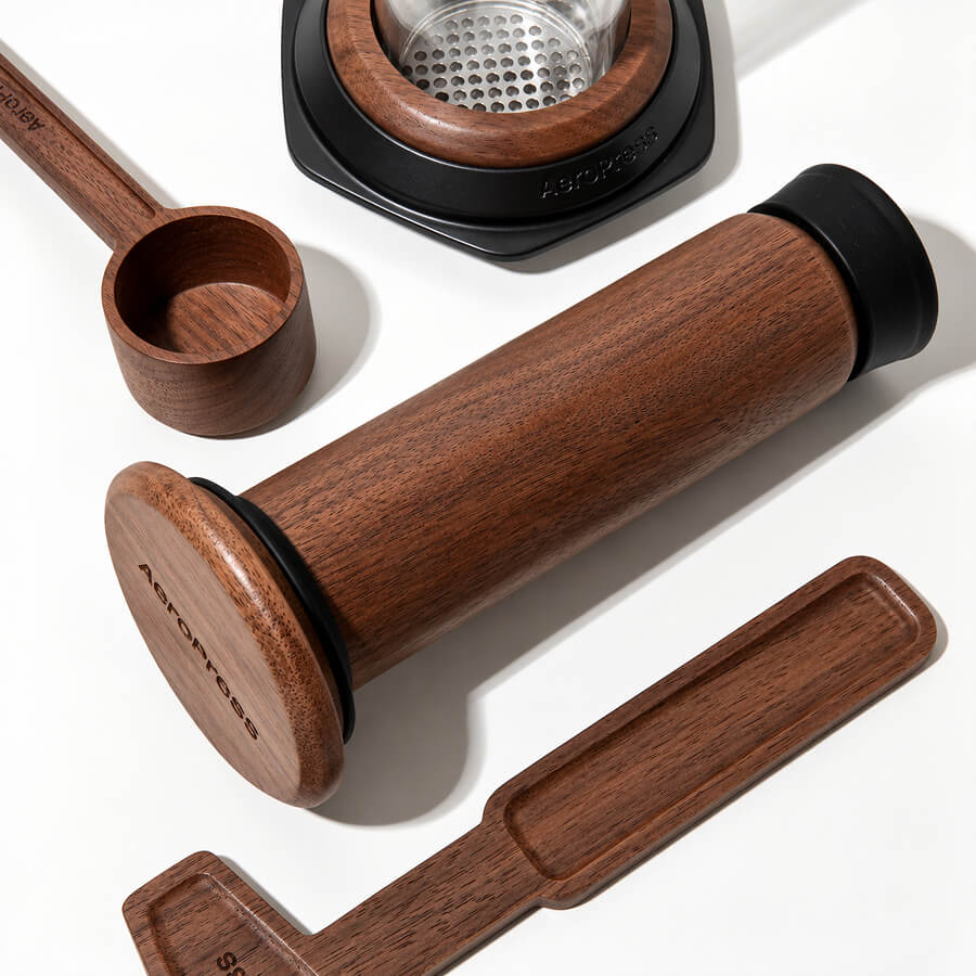 Solid walnut AeroPress plunger, scoop and stirrer beside the glass brewing chamber