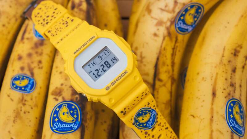 Yellow BAIT Yamagata's Finest G-Shock DW5600 lying across ripe bananas.
