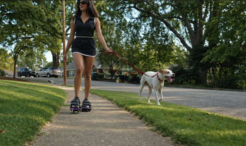 Outdoor dog-walking lifestyle photograph; black Dusk worn over shoes; visible illuminated strip; no overlay