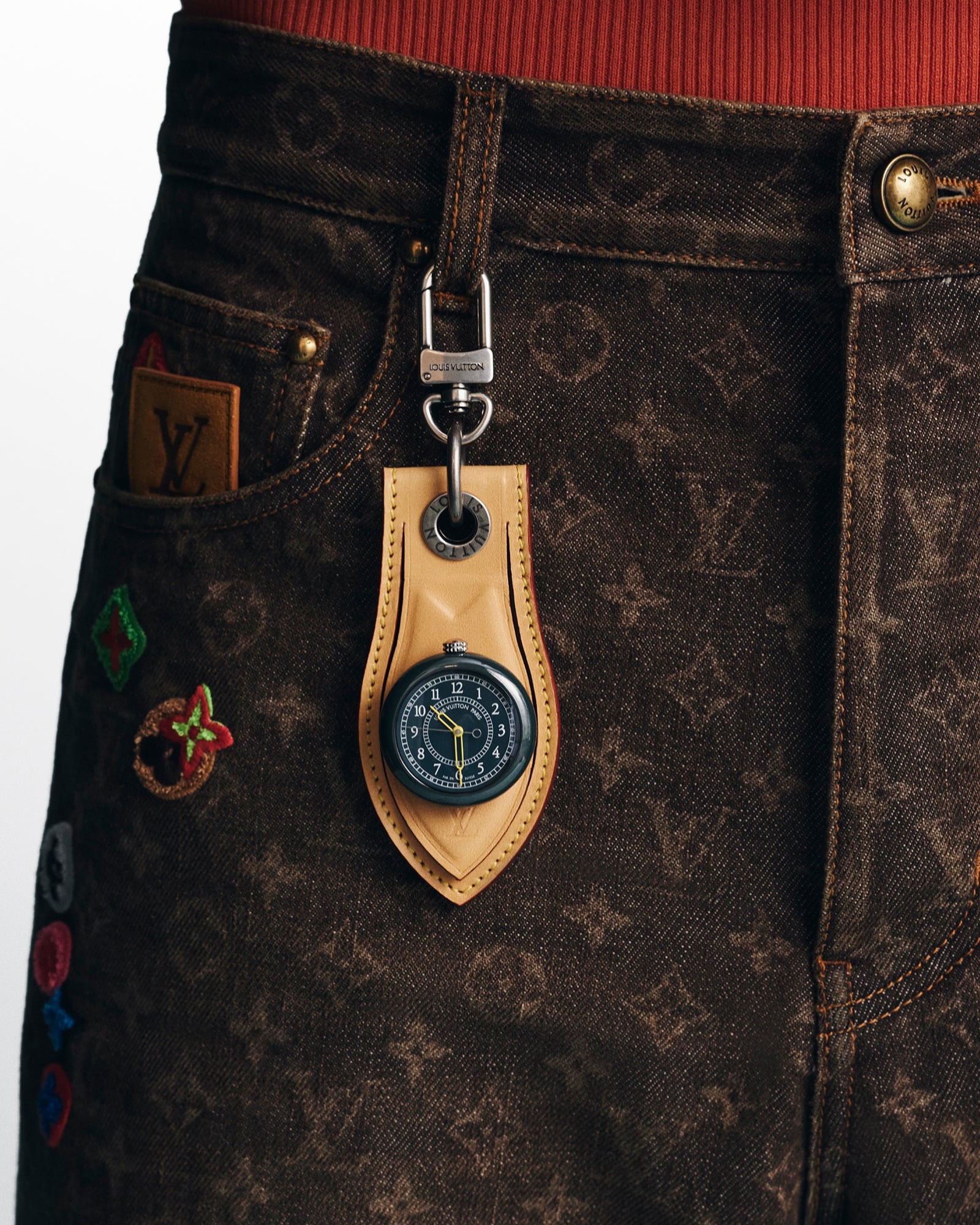 Green Louis Vuitton Monterey in a tan leather holder clipped to a belt loop.