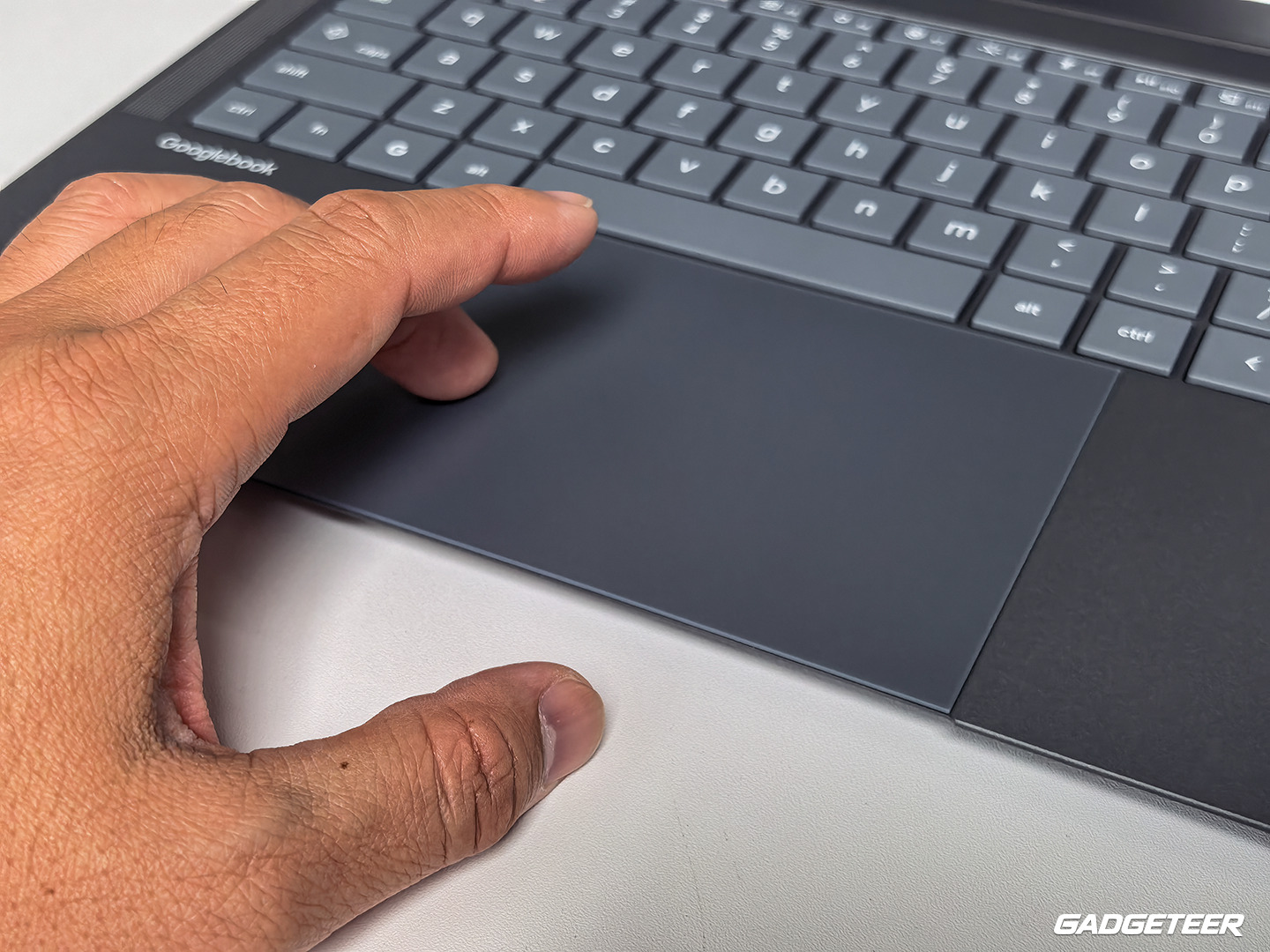 A hand using the ASUS Googlebook 14 glass haptic touchpad.