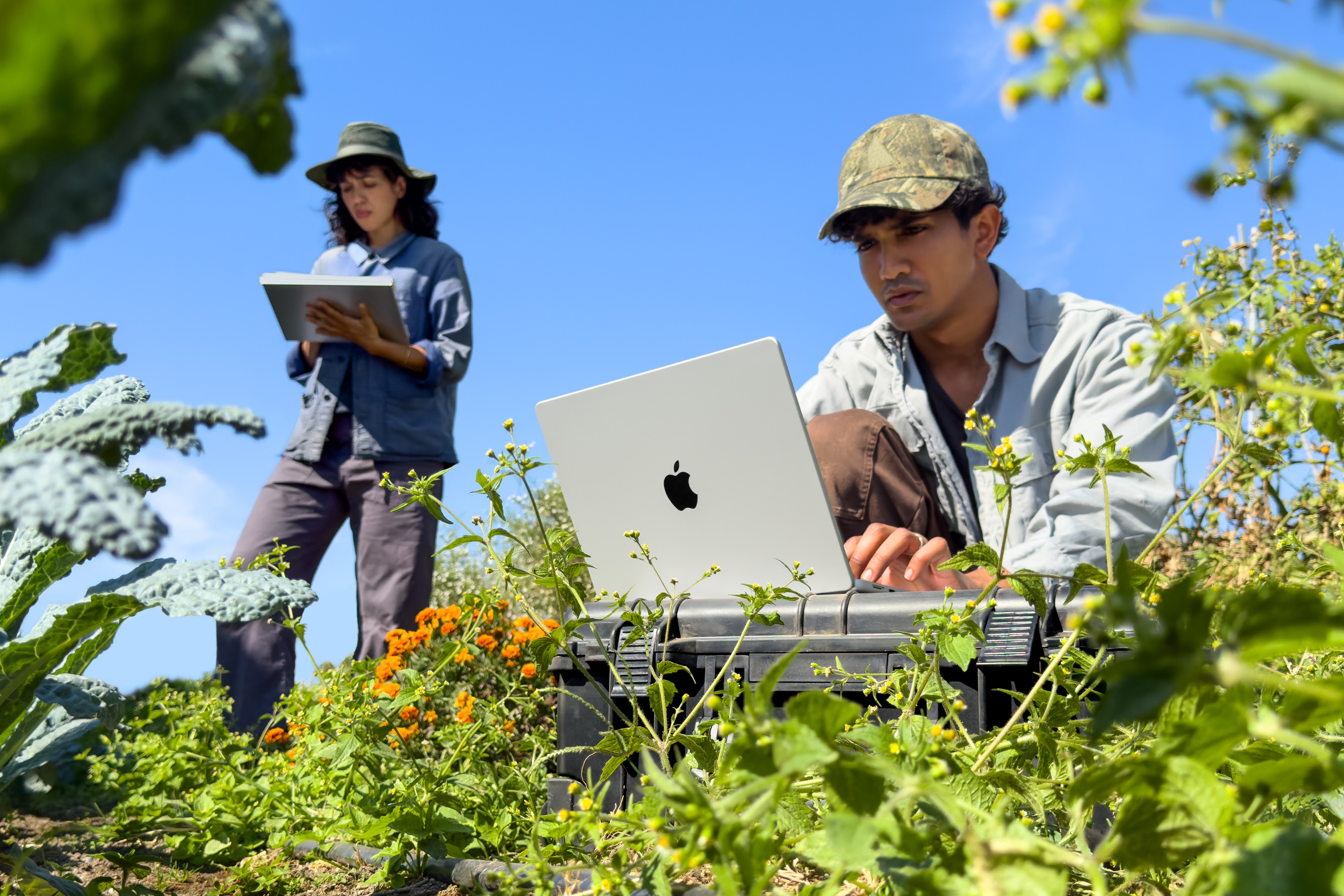 A person using a silver 14-inch M6 MacBook Pro outdoors.