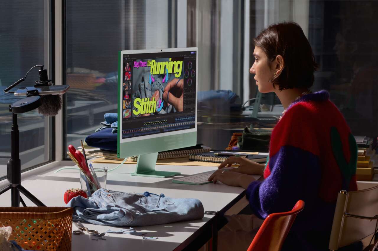 A green M6 iMac on a desk beside a person editing a sewing tutorial.