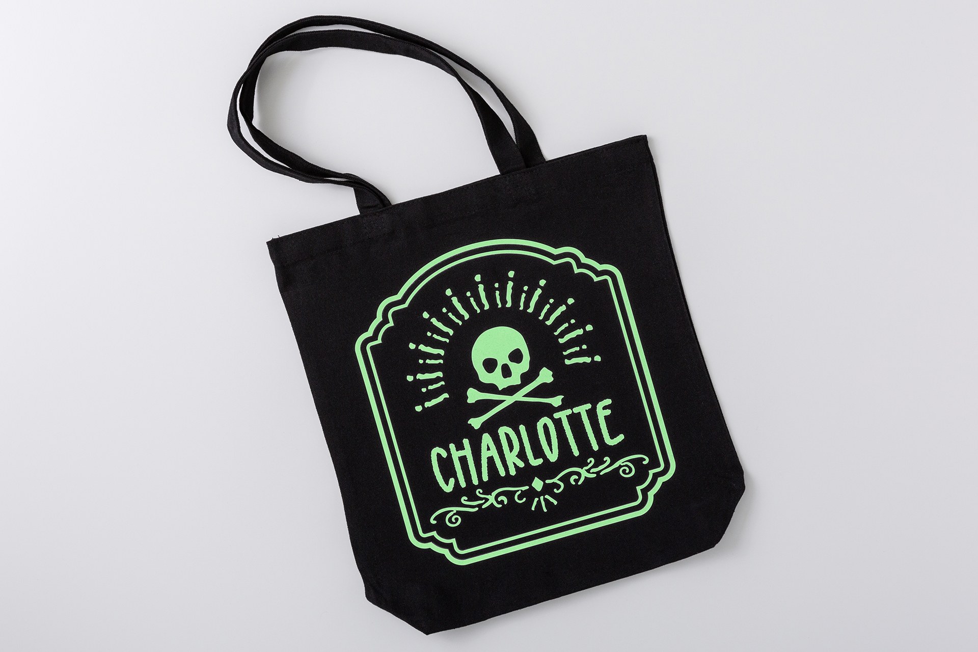 Black fabric tote with a green skull-and-crossbones design