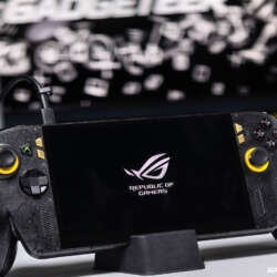 Black and gold ASUS ROG Xbox Ally X20 on a stand with its display powered on.