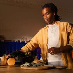 Apple HomeView on a kitchen counter beside a person preparing vegetables.