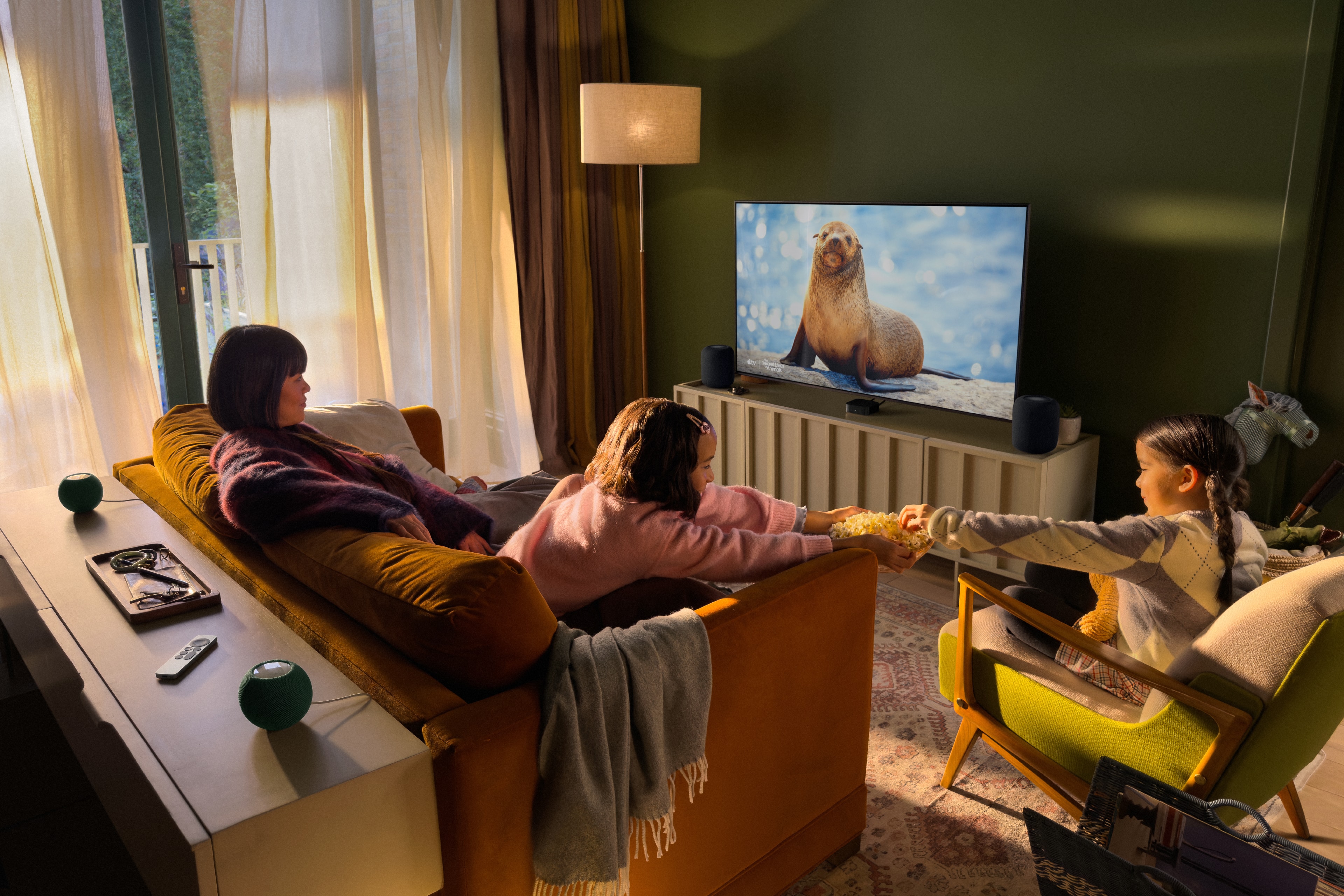 Second-generation HomePods at the front and HomePod mini 2 speakers behind the seating area in an Apple TV surround setup.