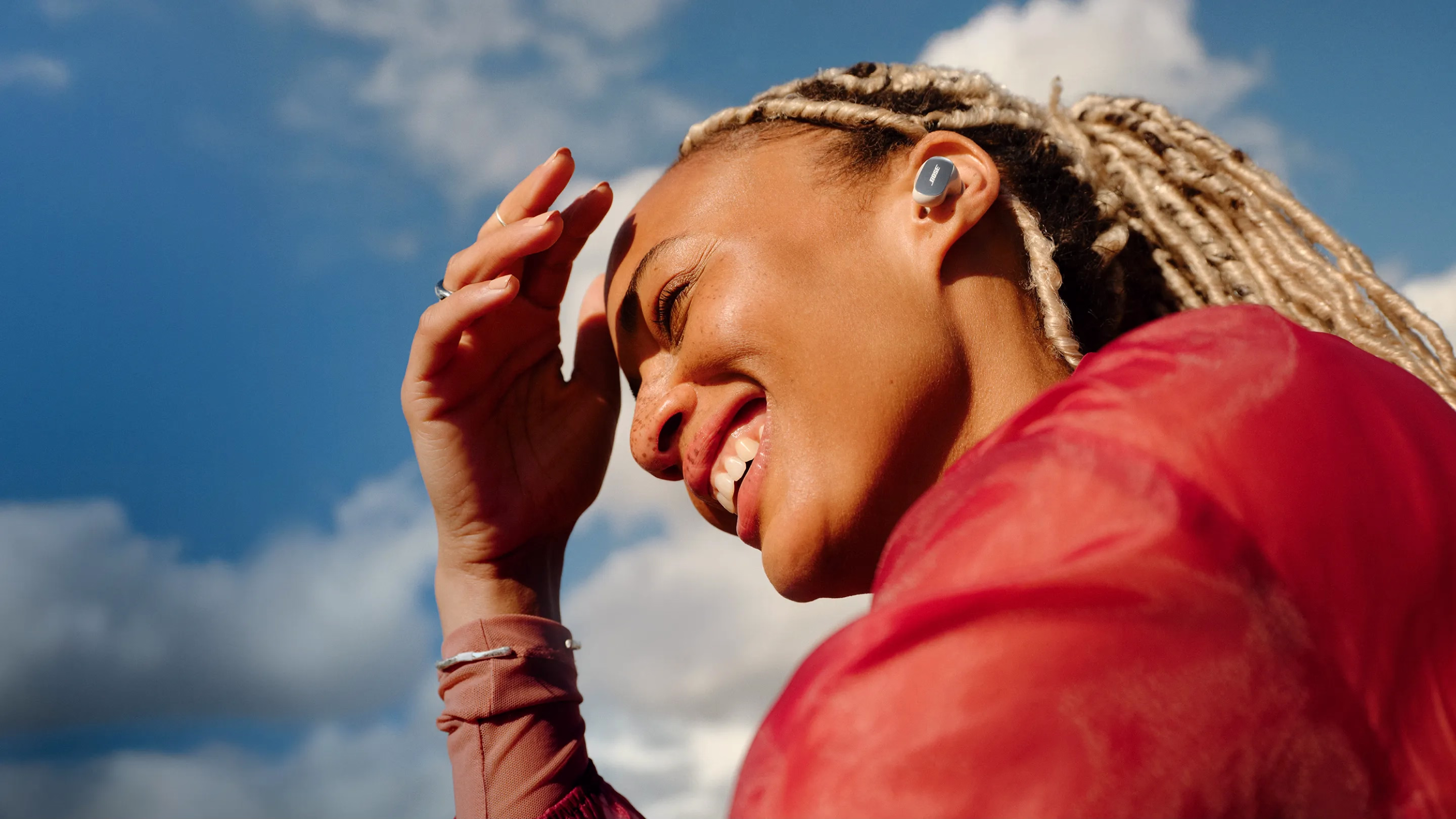 A person wearing white Bose QuietComfort Ultra Earbuds (2nd Gen) outdoors