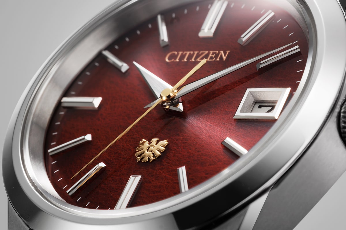 Close-up of the crimson AQ4100-65X dial showing the paper texture, gold-colored seconds hand and eagle
