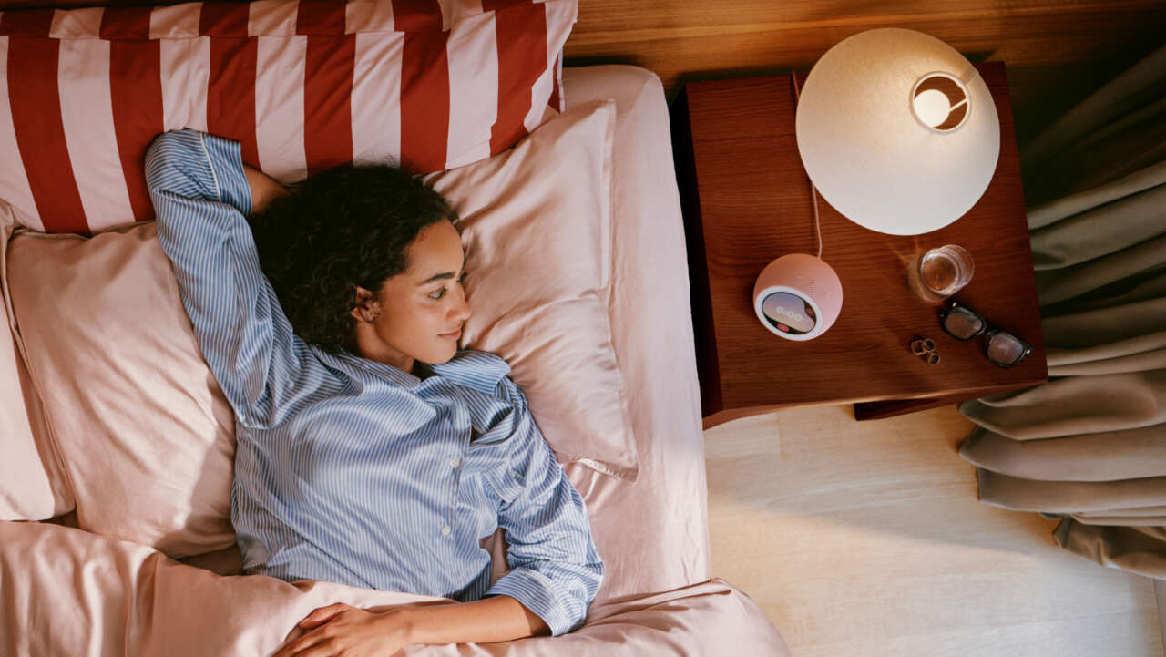 Coral Pink Echo Time on a bedside table beside a person waking, official Amazon lifestyle photograph