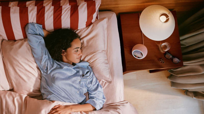 Coral Pink Echo Time on a bedside table beside a person waking, official Amazon lifestyle photograph