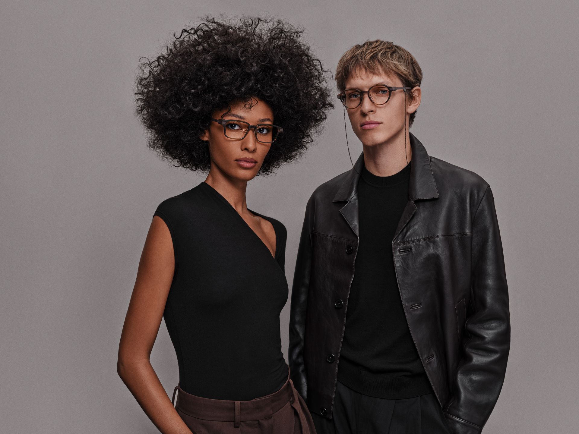Two models wearing Even G2 Brown 2 glasses, with a chain attached to the round frame.