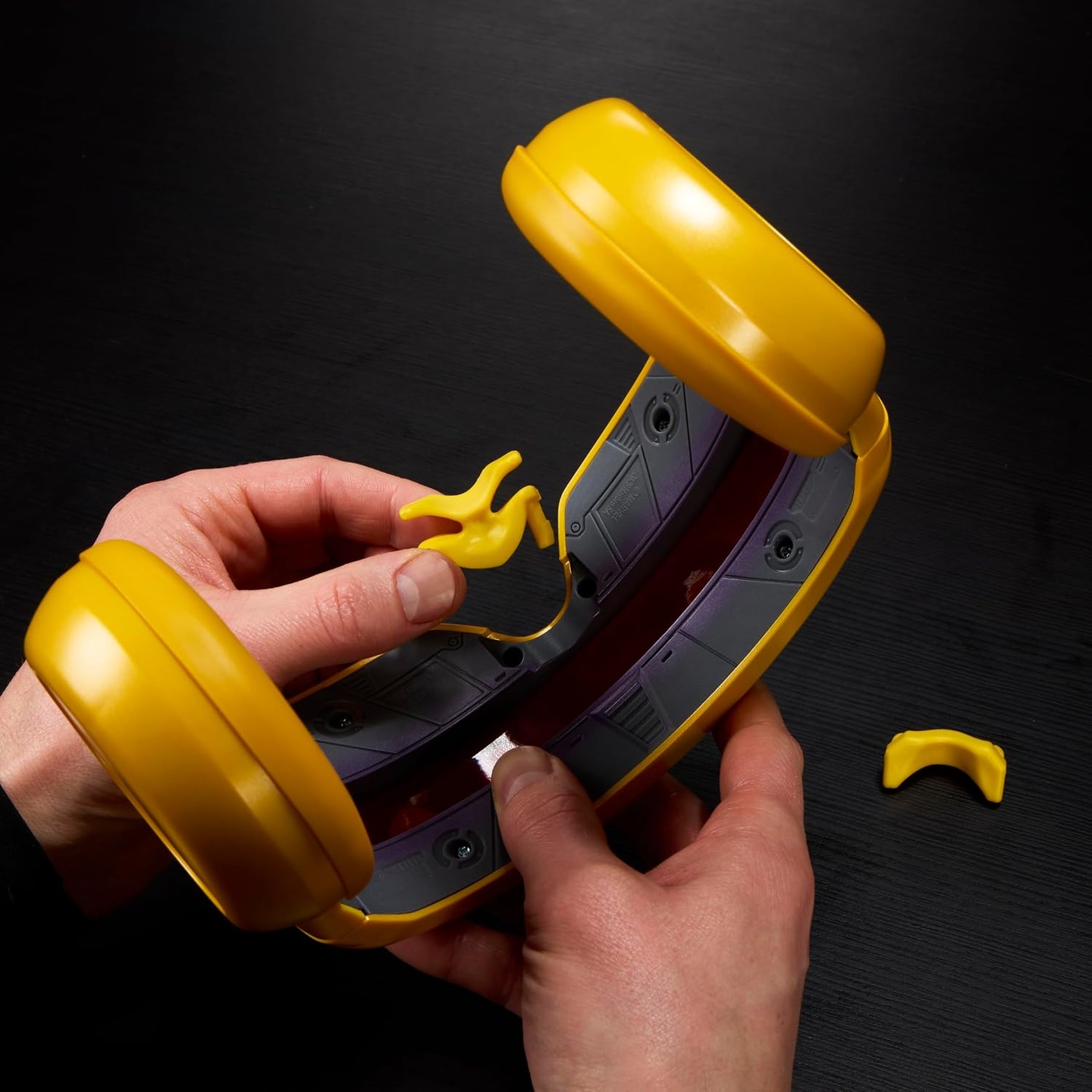 Close-up of hands demonstrating interchangeable nose-bridge pieces inside the Hasbro Cyclops visor.