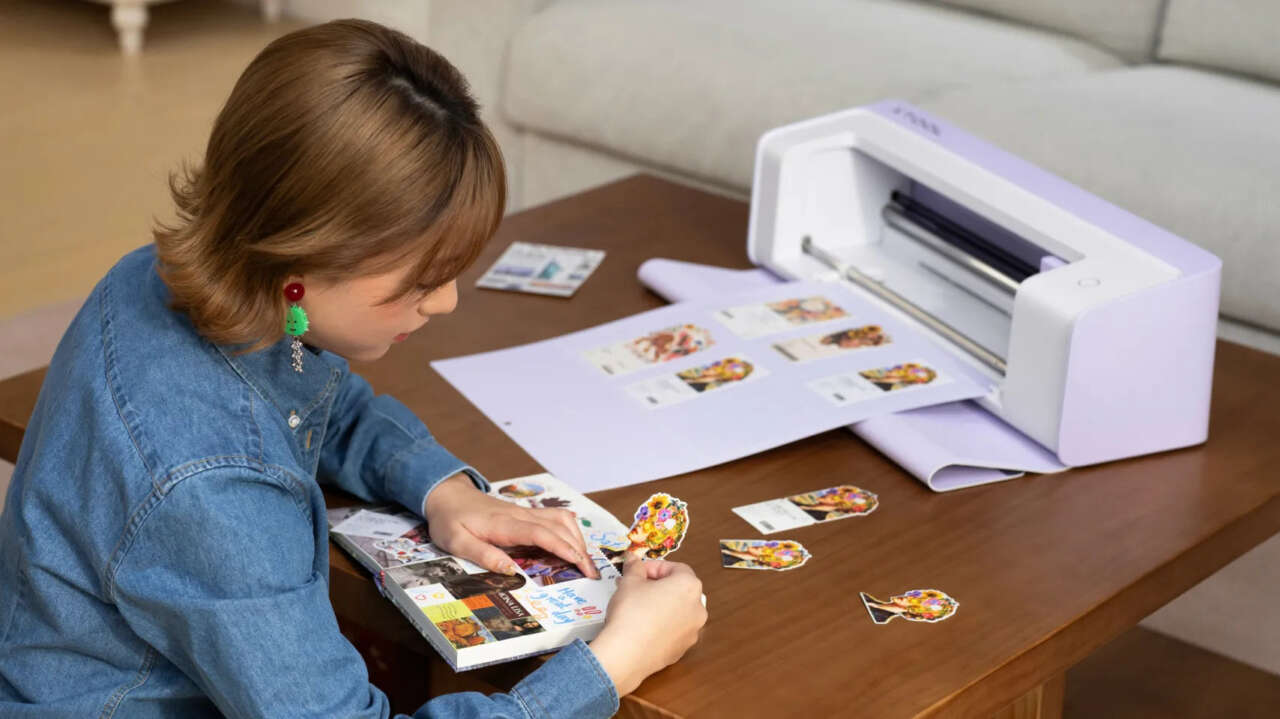 xTool C1 on a craft table with a sheet of printed artwork and cutouts