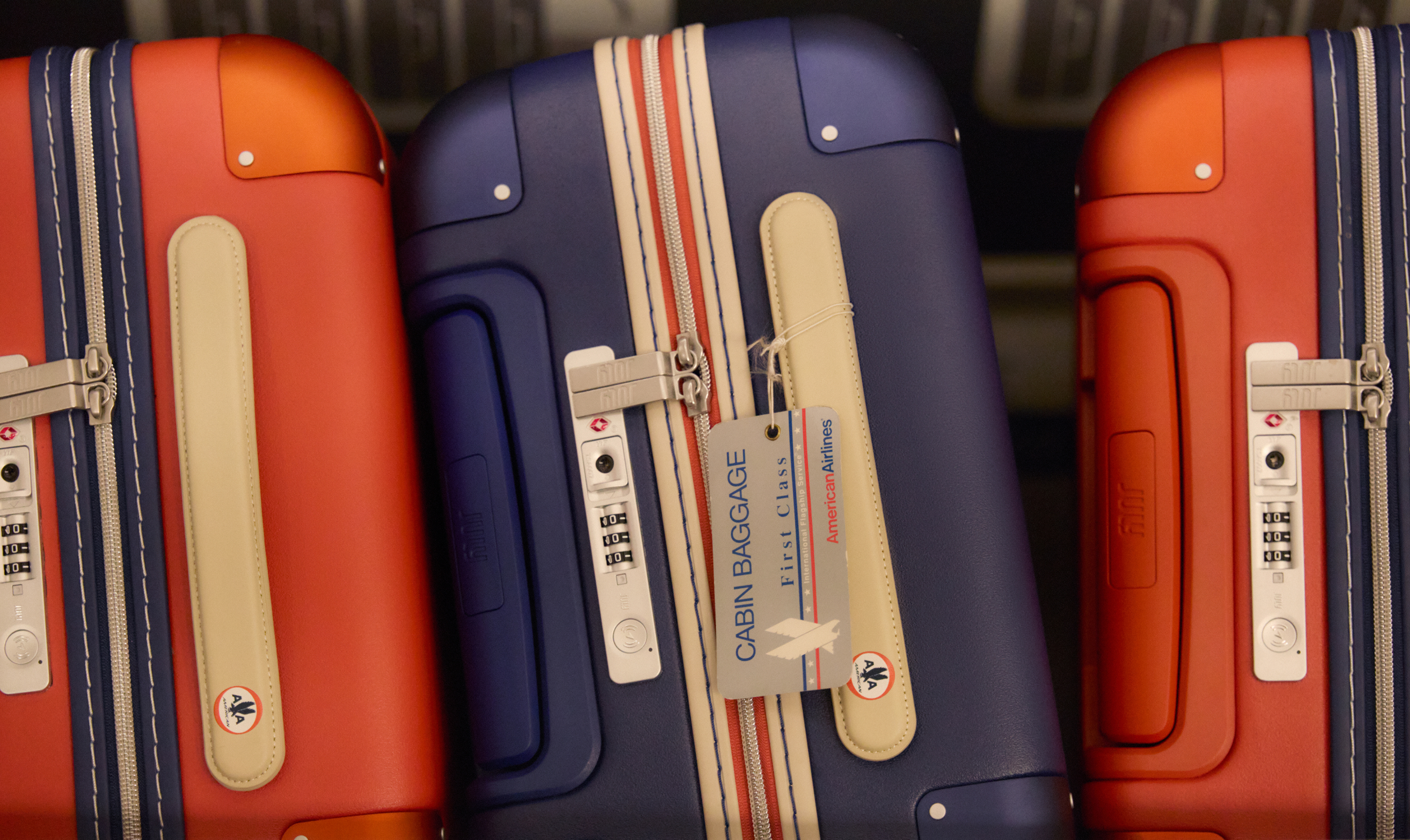 Red and navy July x American Airlines cases with contrasting trim, leather handles and heritage baggage tags. Image: July.