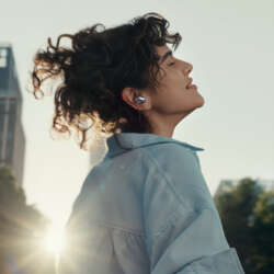 Person outdoors wearing a silver Huawei FreeBuds Neo earbud