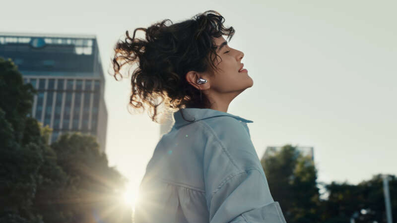 Person outdoors wearing a silver Huawei FreeBuds Neo earbud
