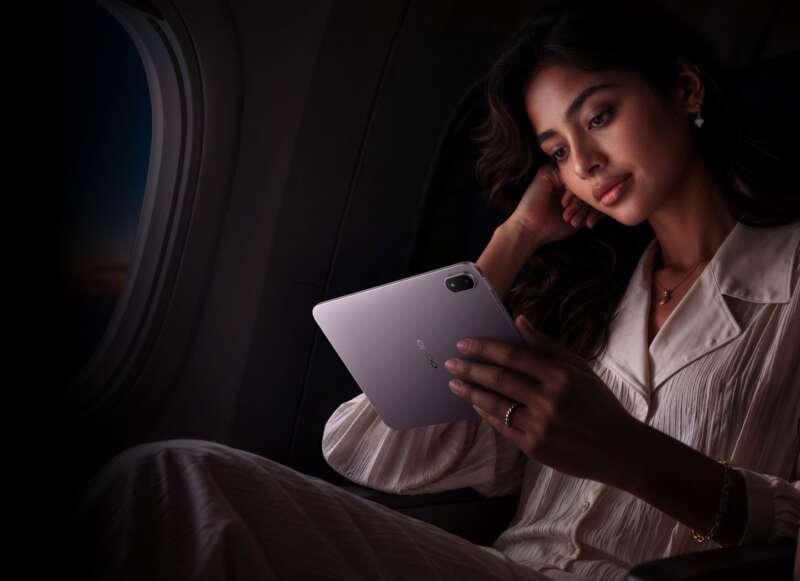 A woman holding the lavender OPPO Pad Mini in an airplane cabin.