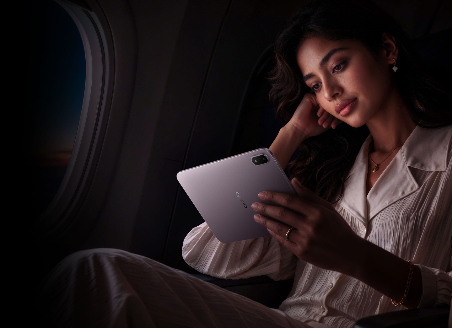 A woman holding the lavender OPPO Pad Mini in an airplane cabin.
