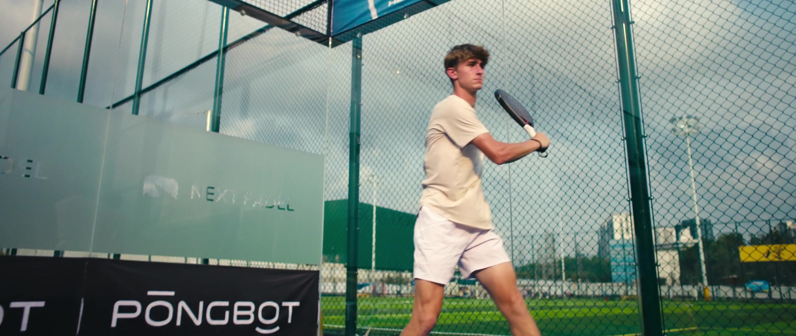 Padel player with a perforated racket on an enclosed court in Pongbot’s Aura demonstration.