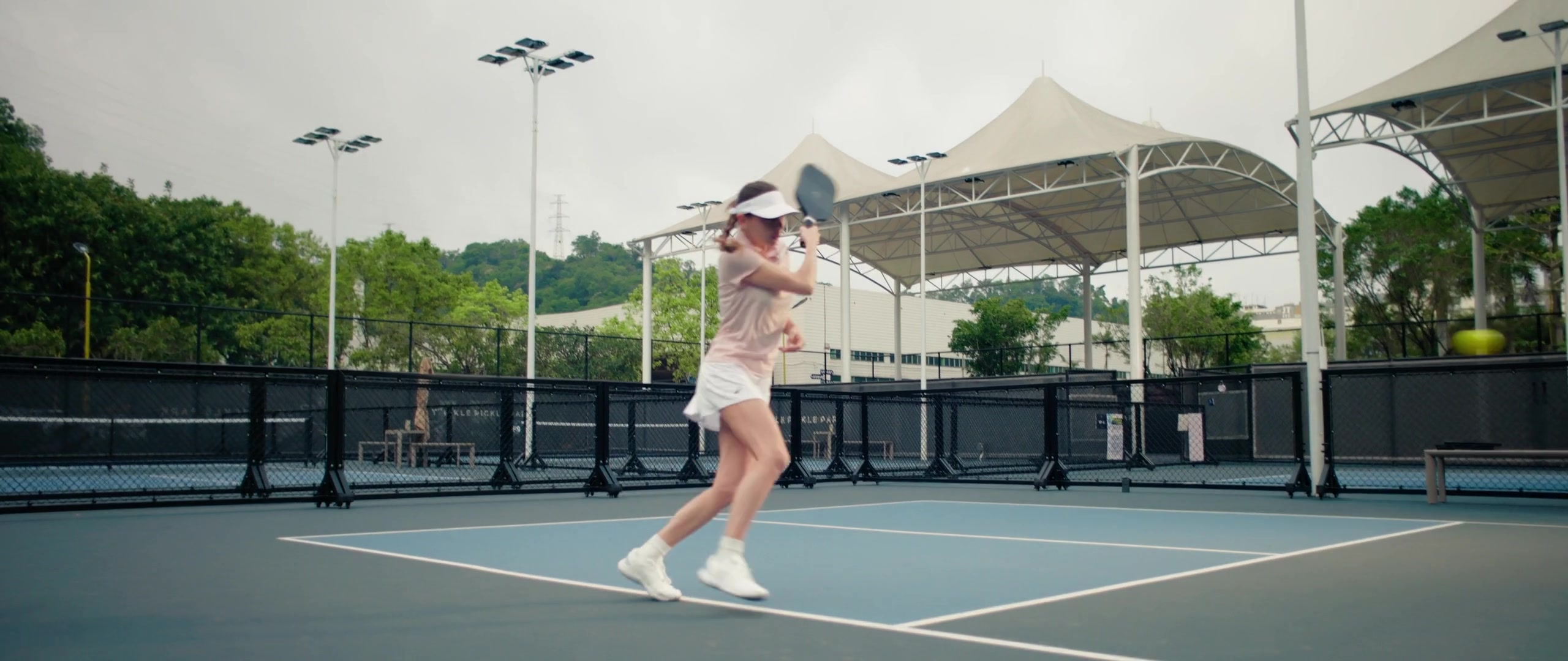 Pickleball player swinging a paddle on a marked court in Pongbot’s Aura demonstration.