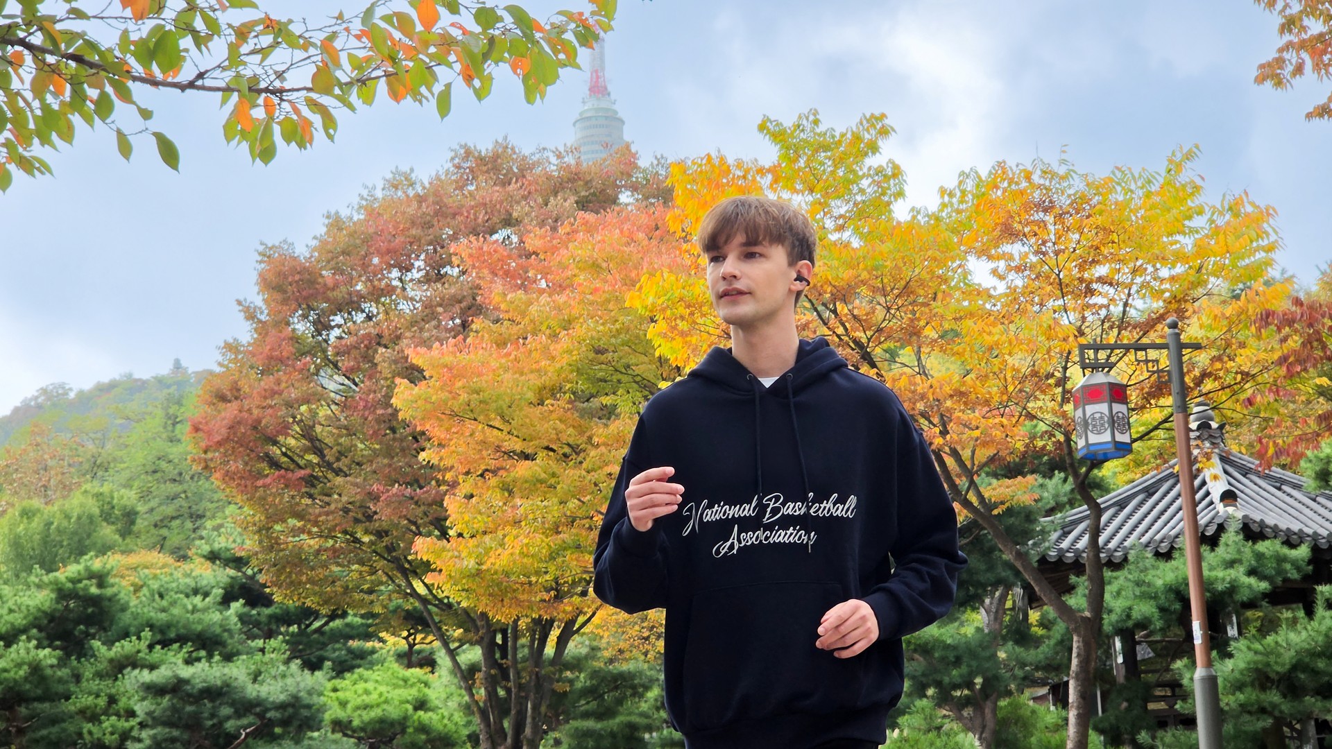 Runner wearing black Samsung Galaxy Buds On among autumn trees