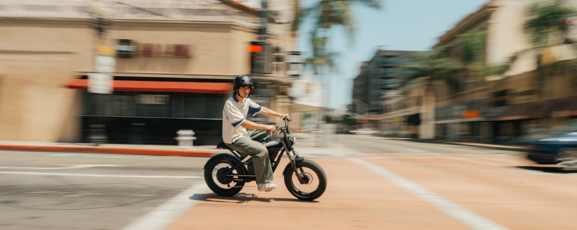 Helmeted rider traveling across a city street on the Segway Xyber Air