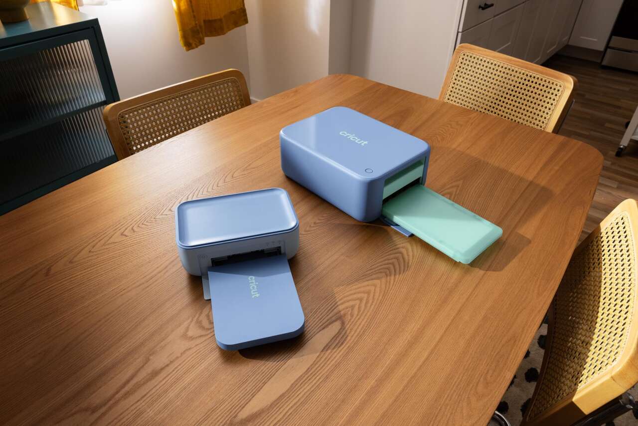 Cricut StickerPix Print and Print + Cut machines on a wooden table.