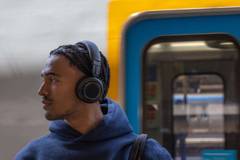 Person wearing black TDM Neo headphones beside a train