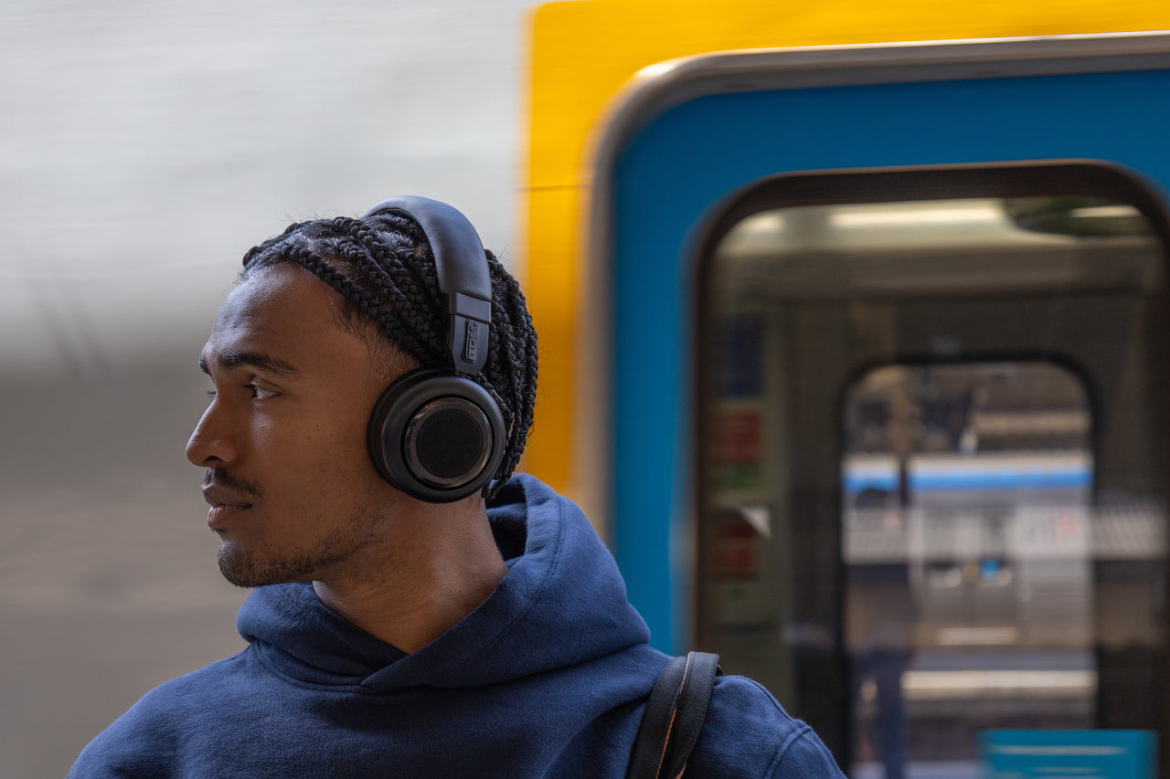 Person wearing black TDM Neo headphones beside a train